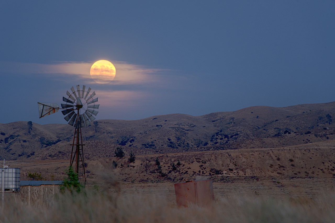 A windmill silhouetted against a rising Moon, illustrating May 2026 skywatching conditions