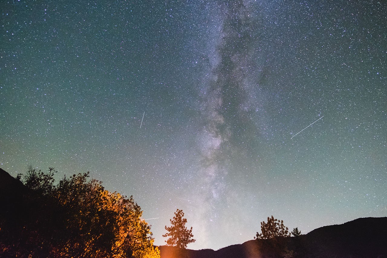 Orionid meteor streaking across the night sky near a mountain ridge