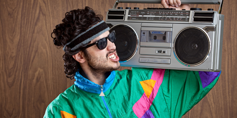 Young person in 1980s neon tracksuit and mullet holding a boom box