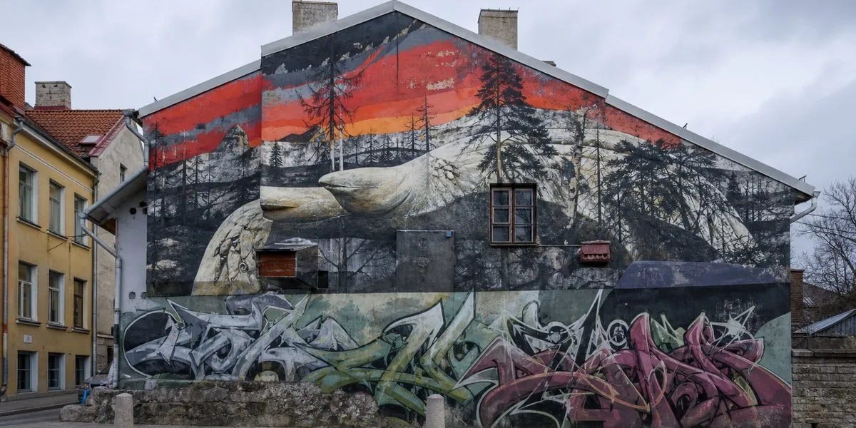 Graffiti with PASR tag over city-commissioned murals in Tallinn, showing tension between unauthorized and official public art
