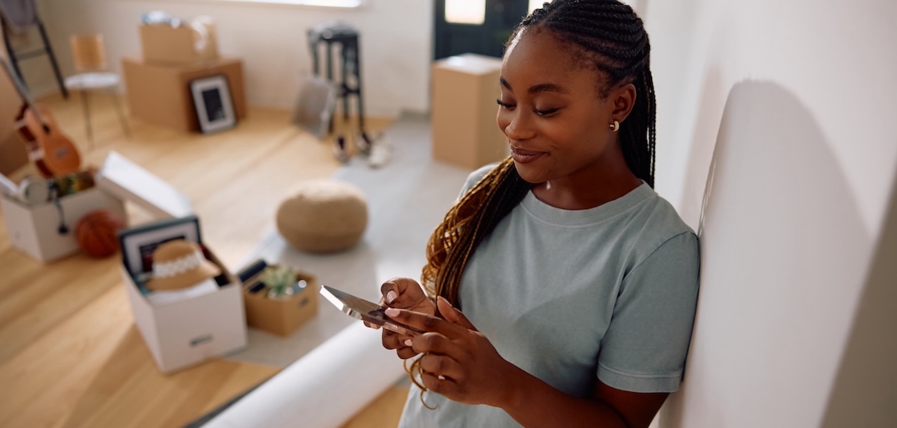 First-time buyer smiling at phone after using a new homeownership PropTech app