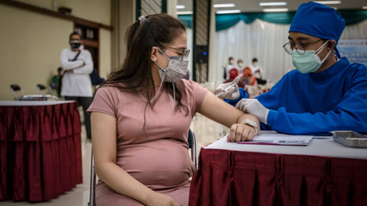 Pregnant woman holding her belly, illustrating the topic of maternal vaccination and prenatal health