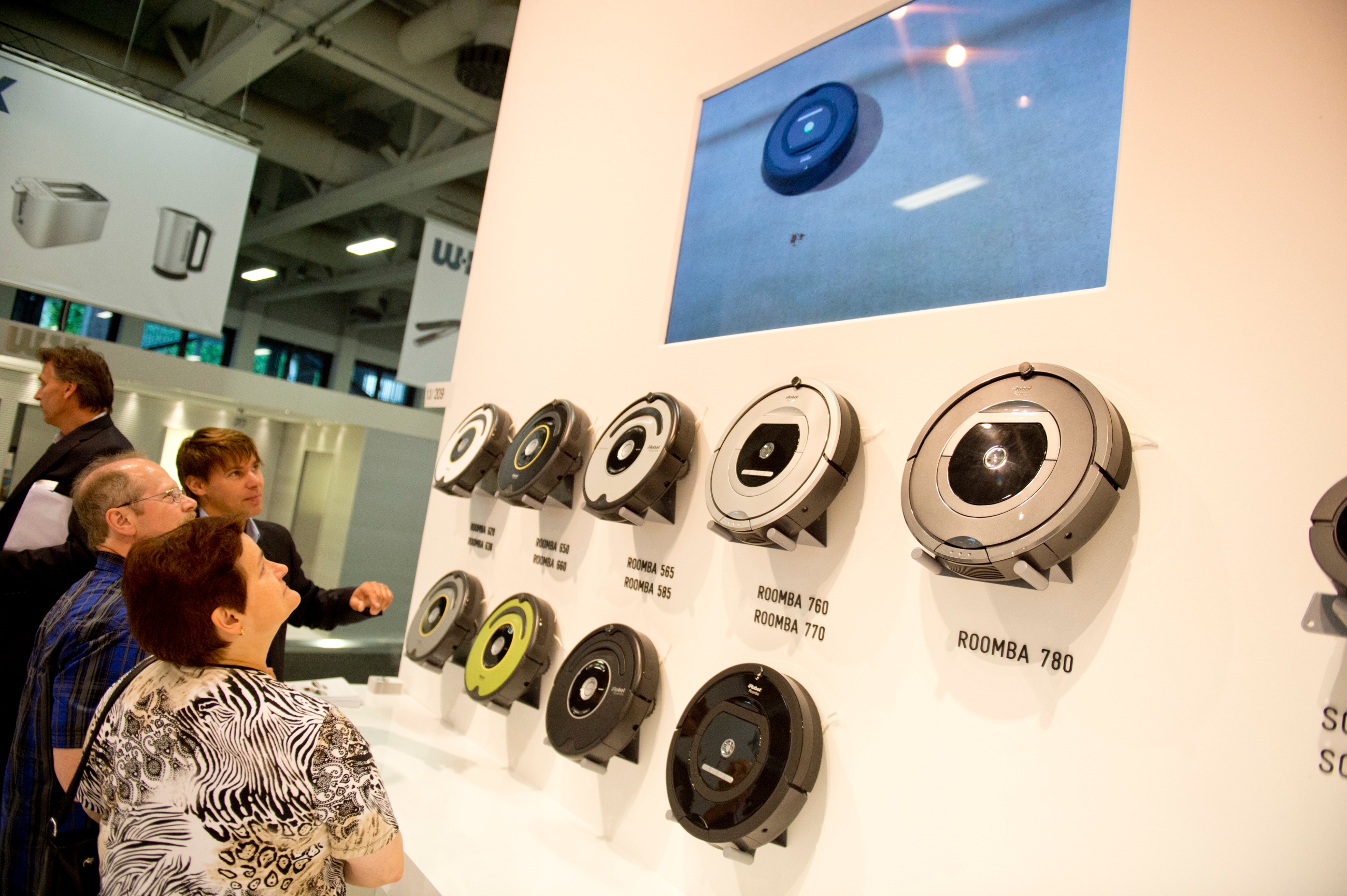 Visitors watch robot vacuums at a trade show
