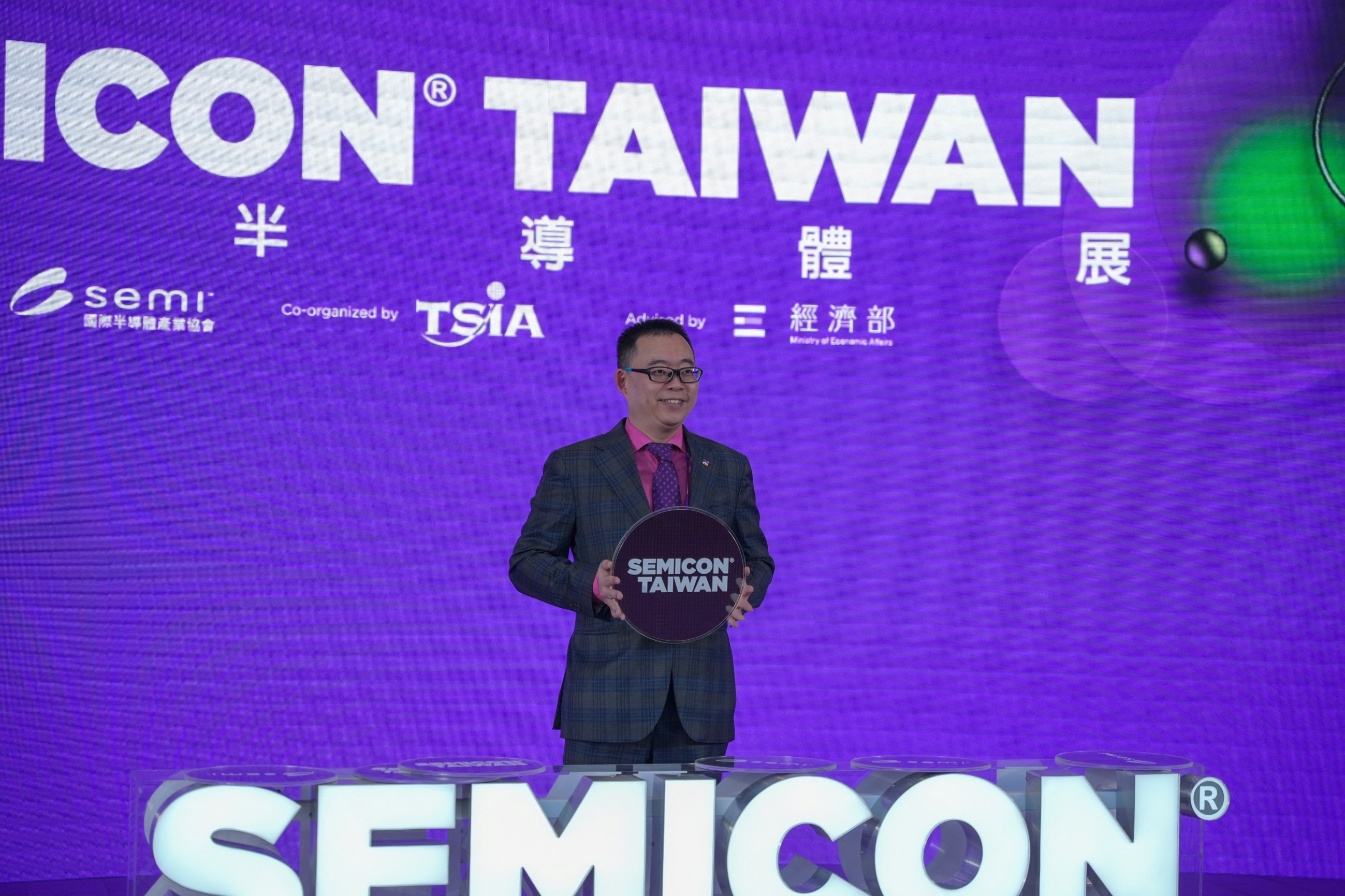 Man holds prop wafer with SEMICON Taiwan logo