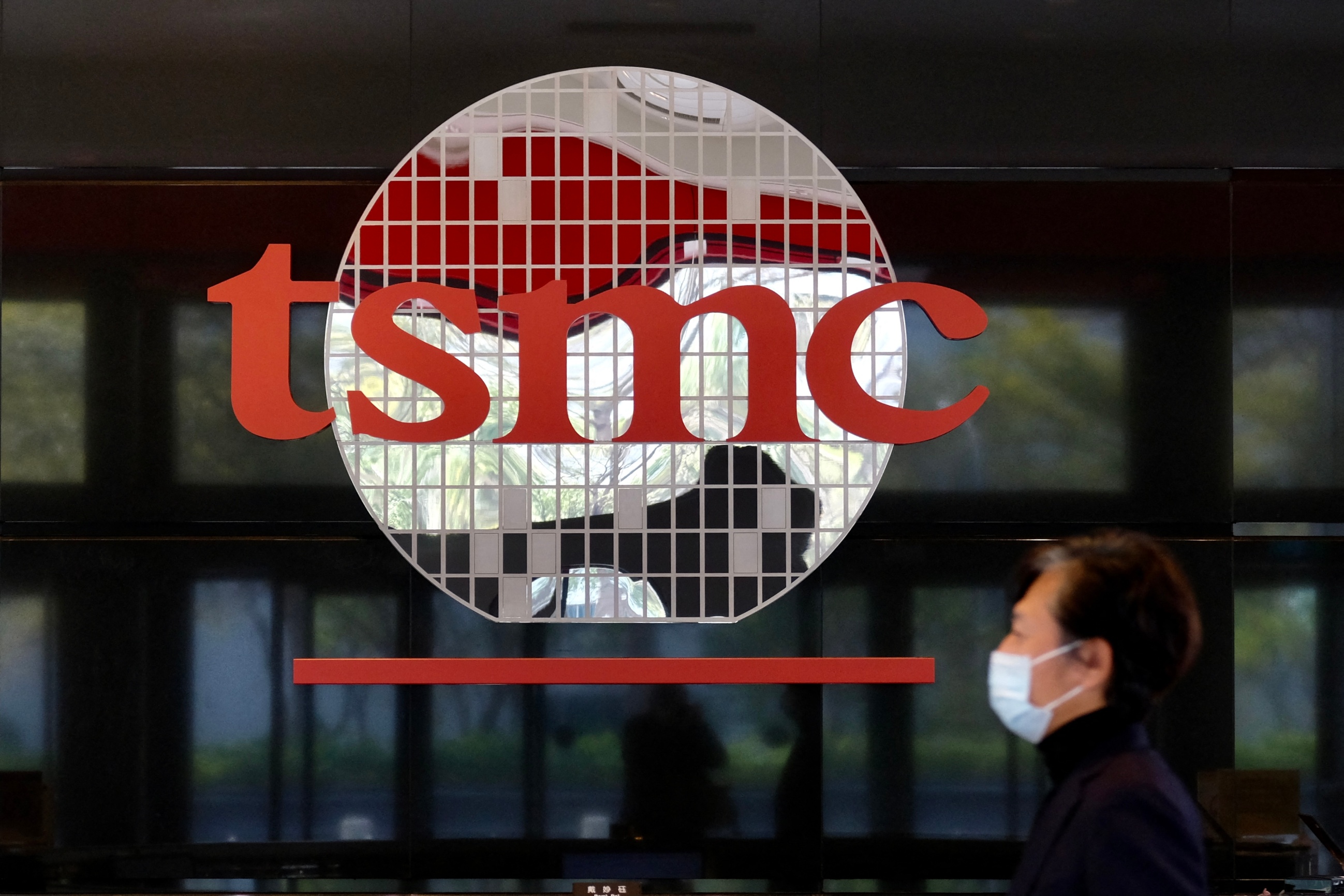 Man walks past TSMC headquarters logo