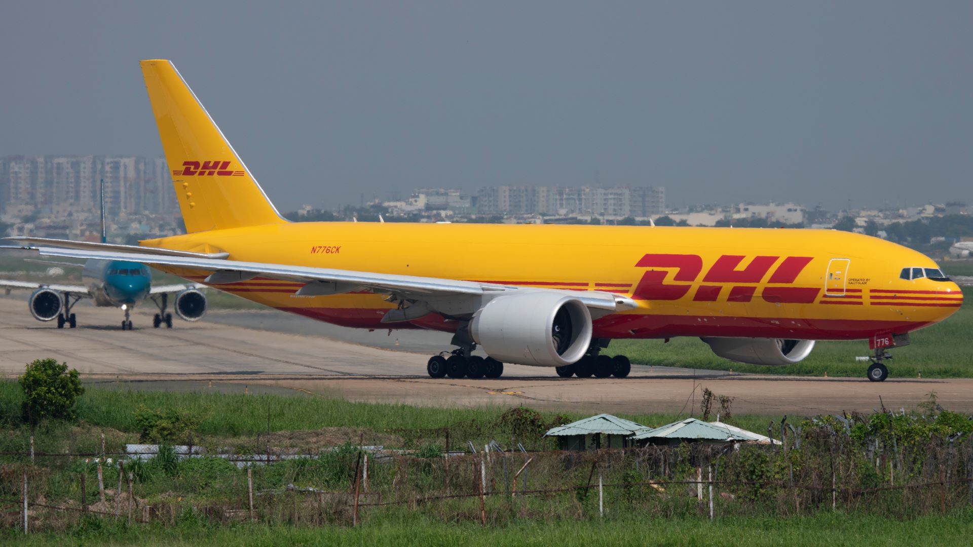 A bright-yellow DHL 777 cargo jet preparing for takeoff on a runway