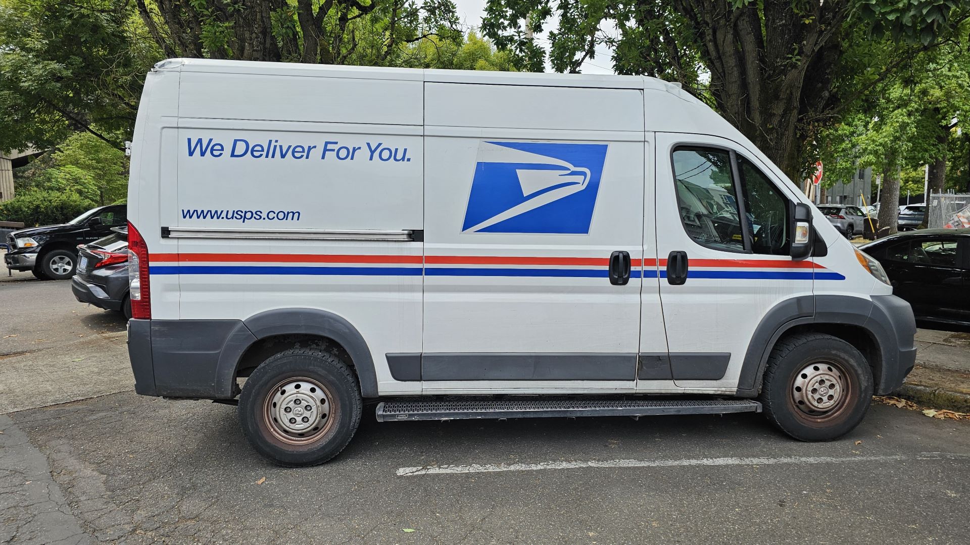 A USPS delivery van parked in a lot, illustrating proposed postal rate changes