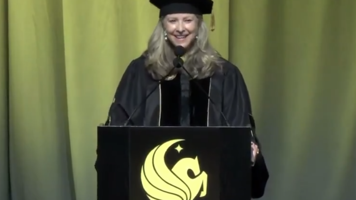 Graduation ceremony with students in caps and gowns reacting to a commencement speech on AI