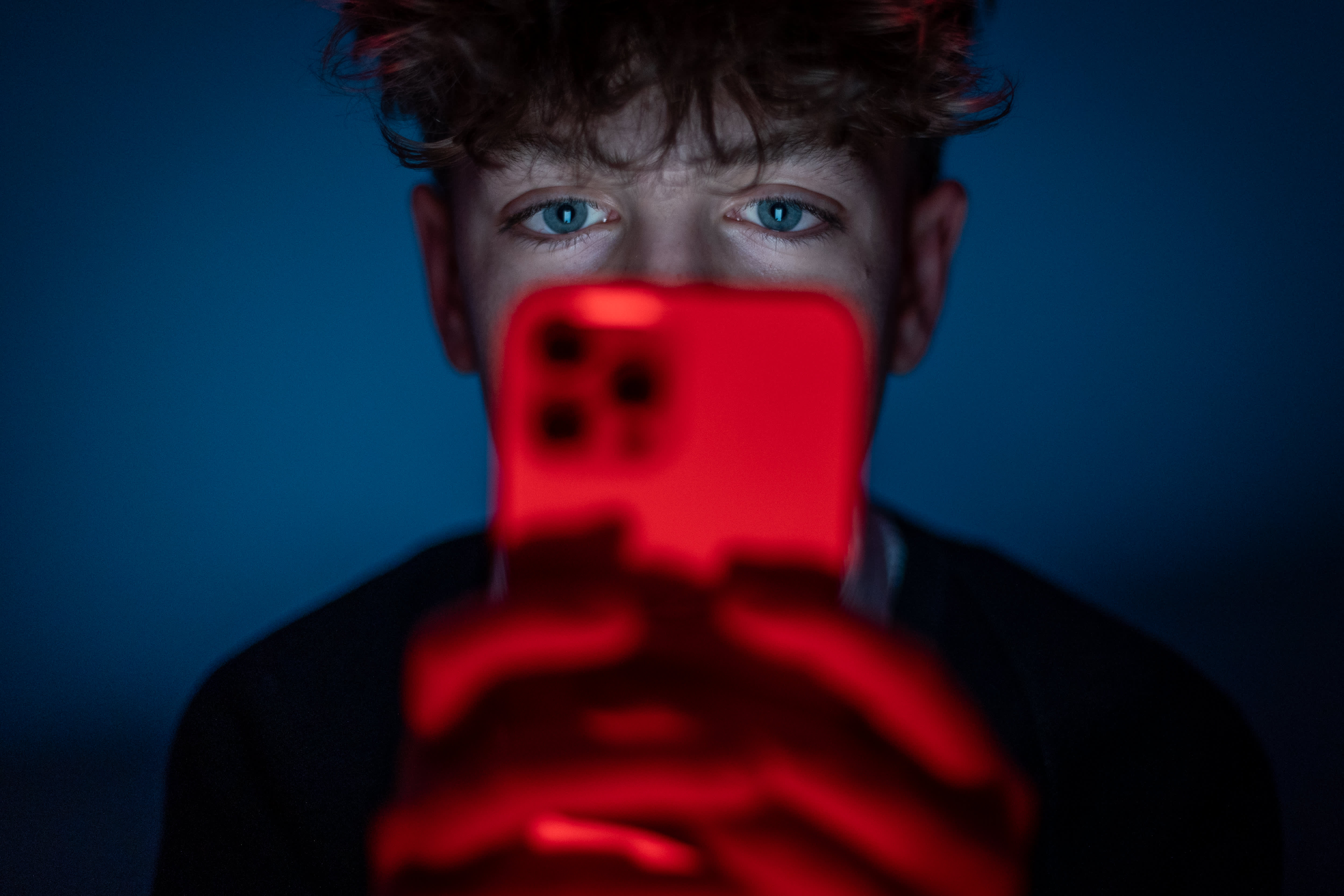 UK teen holding smartphone at night