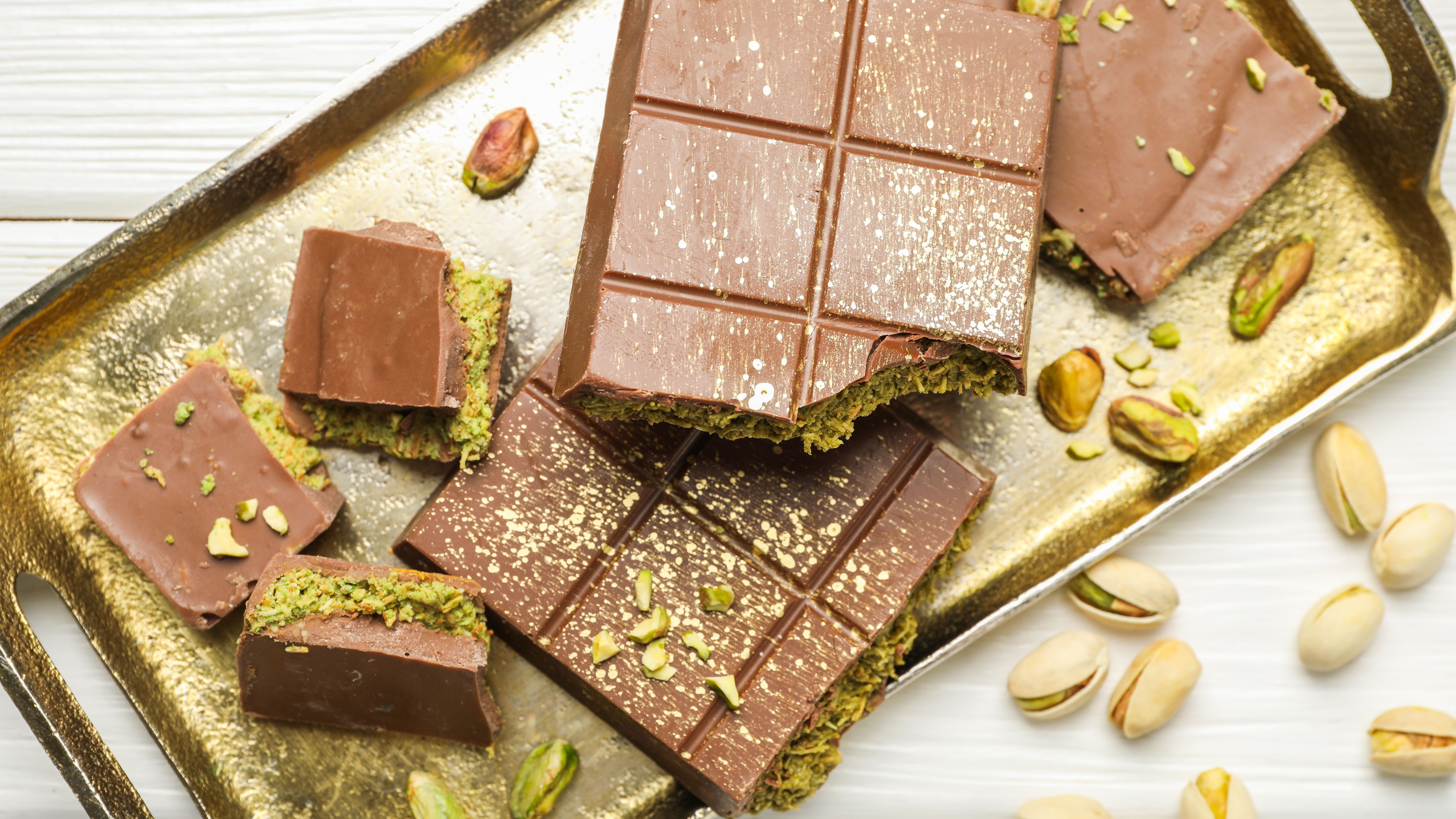 Dubai chocolate bars with pistachios and knafeh on a white wooden table