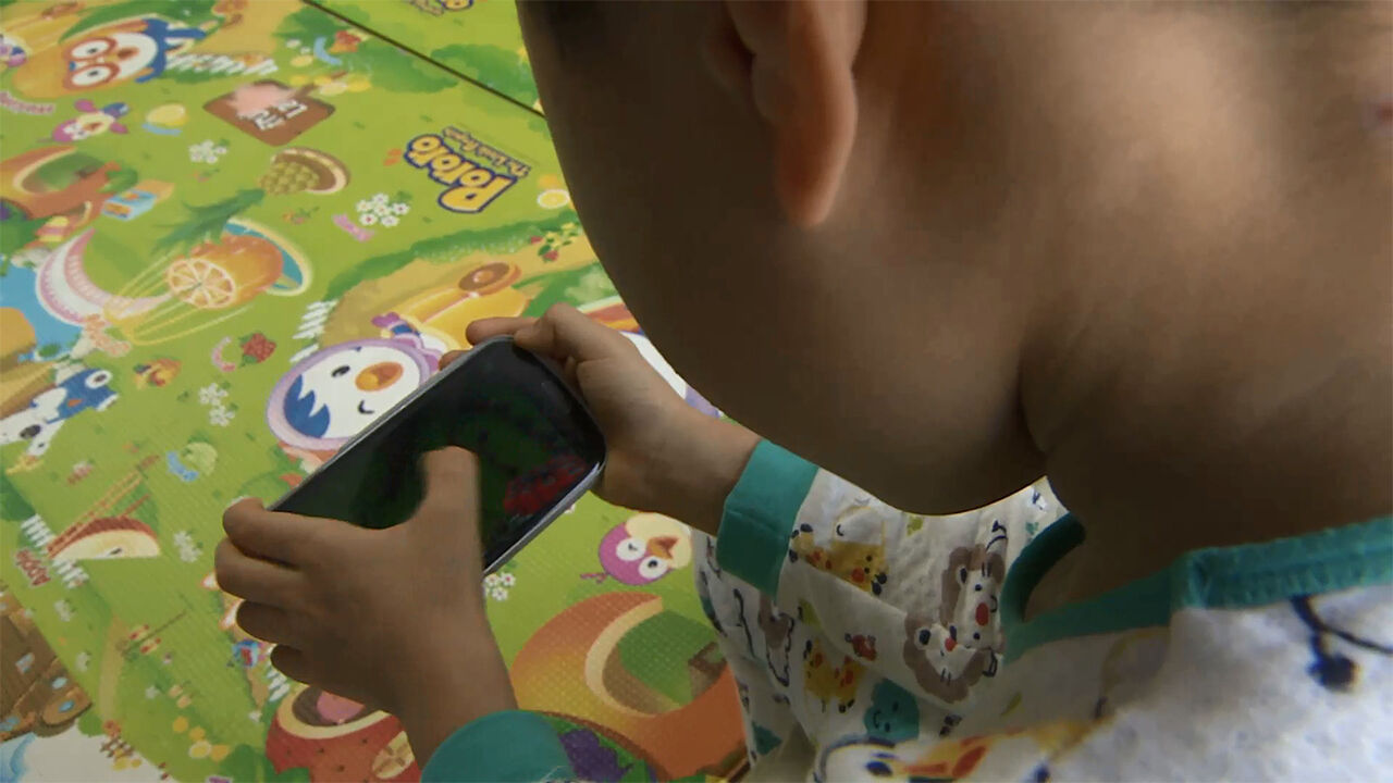 Young toddler with smartphone showing early screen exposure trends