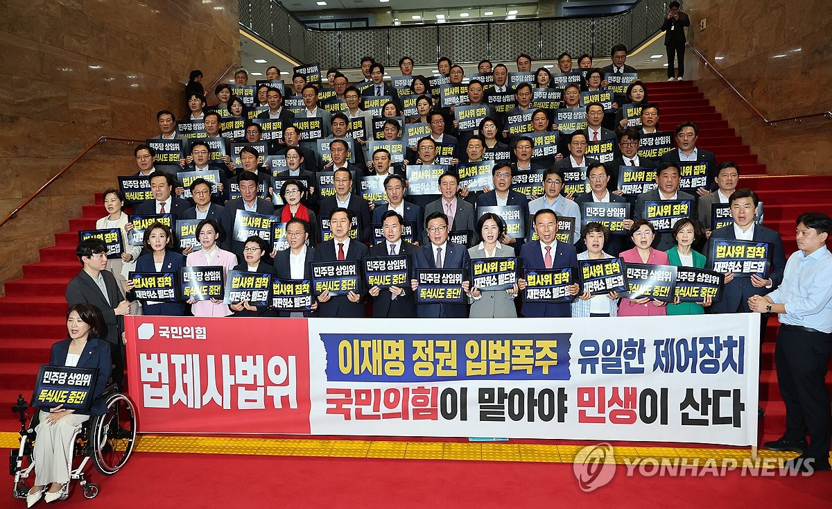 People Power Party members hold protest signs against the ruling party’s unilateral committee chair election.