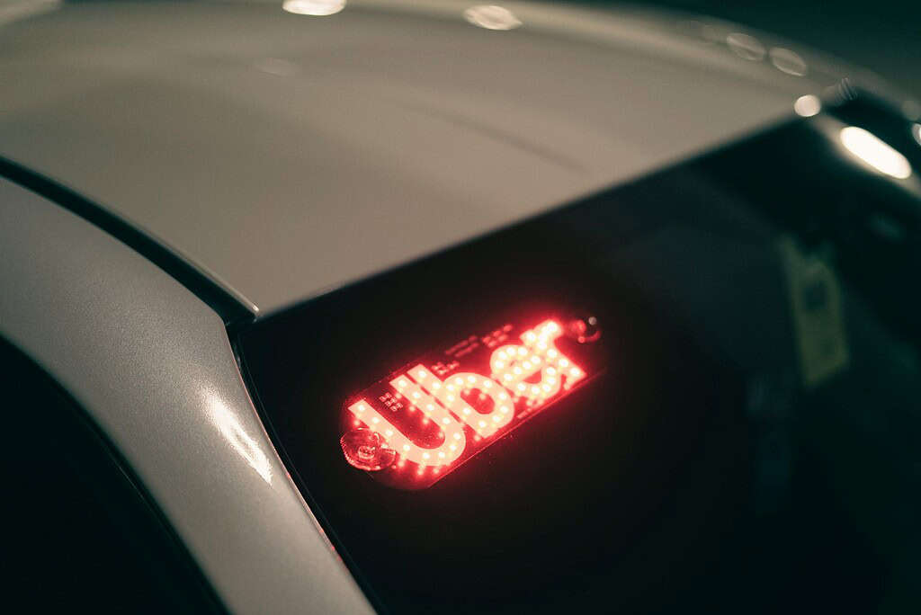 A ride-sharing car with a bright red illuminated sign at night — illustrating the gig workers at the center of New Jersey's new classification rules