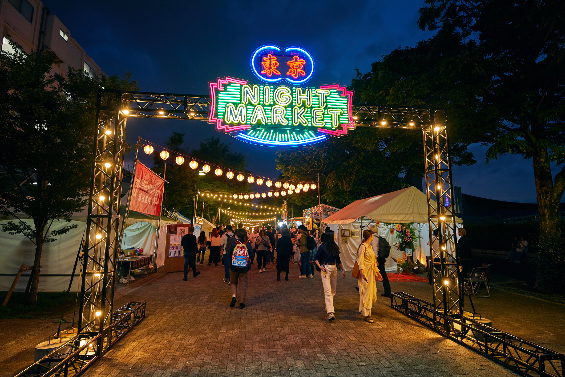 Visitors enjoying street food and live performances at Tokyo Night Market in Yoyogi Park on a sunny spring afternoon