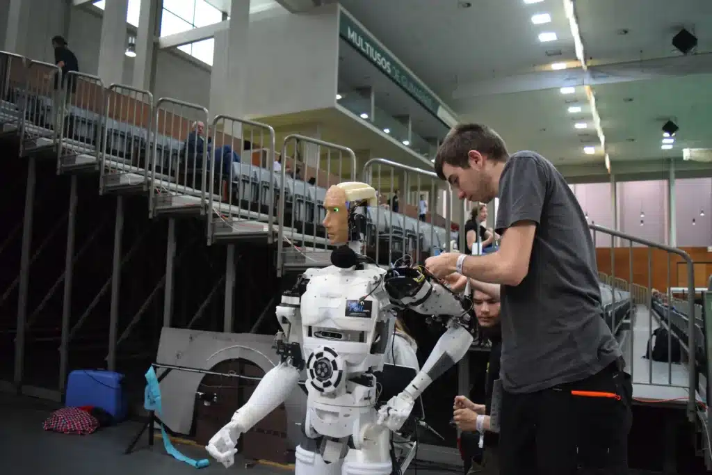 Engineer assembling a humanoid robot at a robotics competition