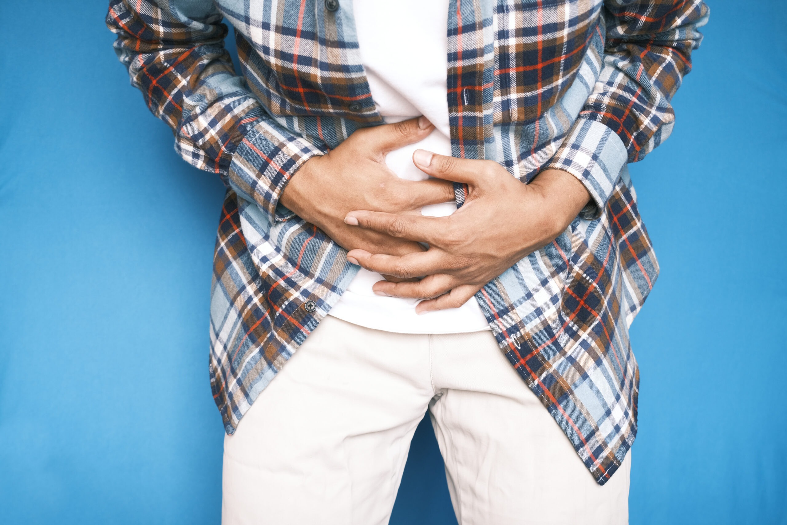 Image of an adult holding their abdomen against a blue background