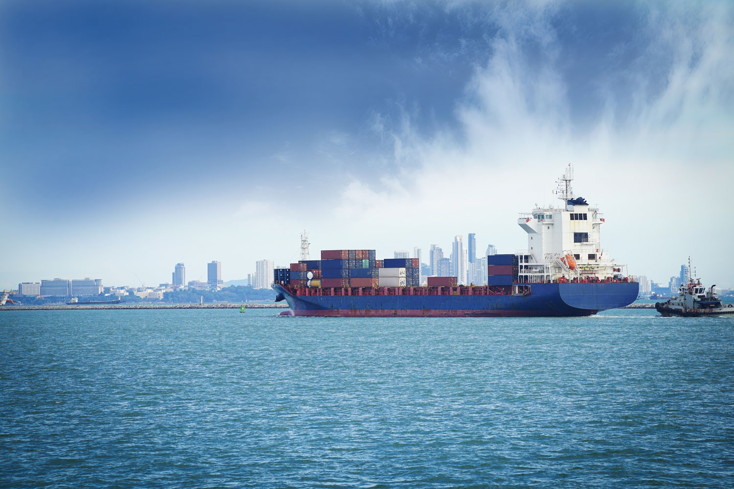 Cargo ship off the shore of a city representing international supply chain pressures