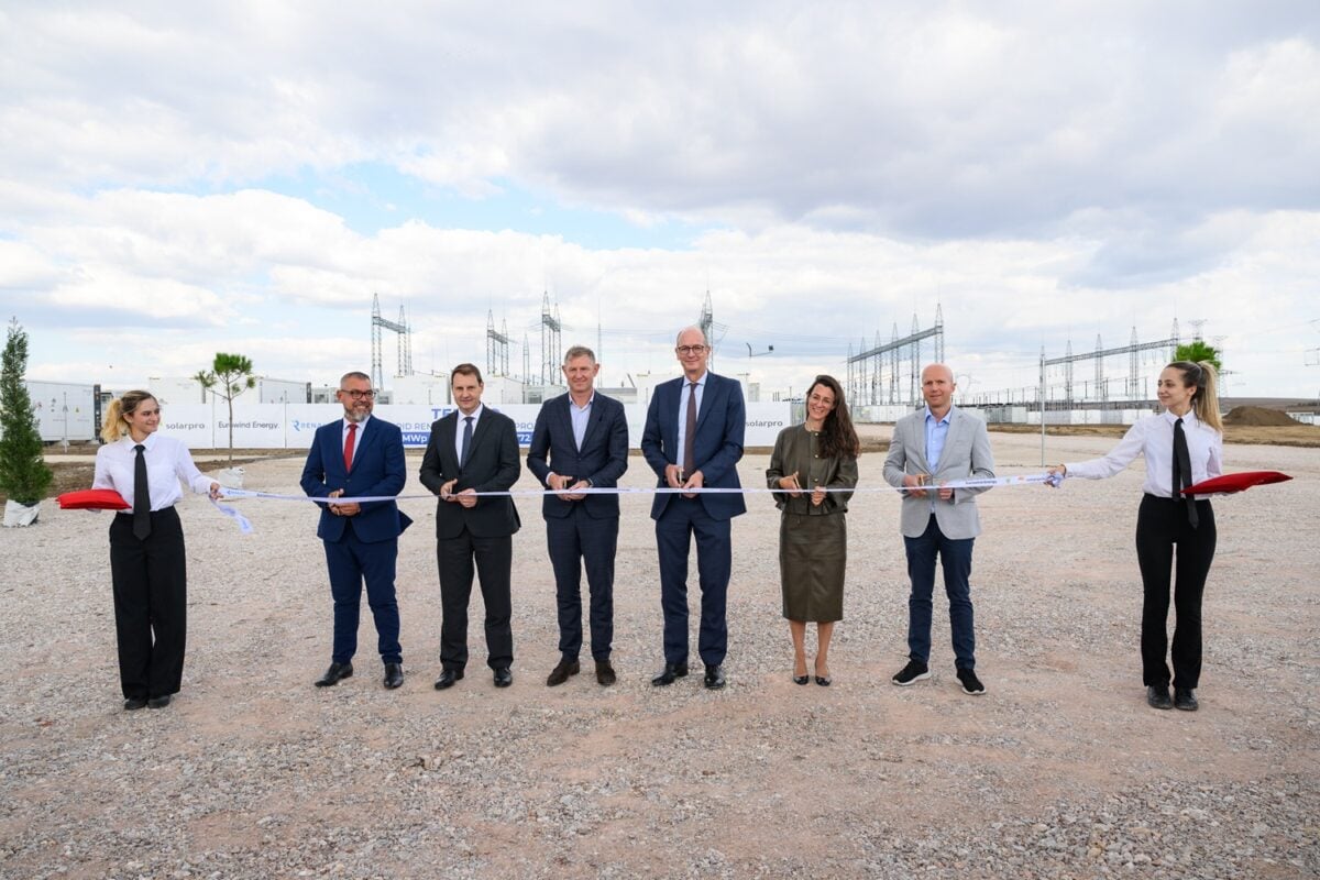 Ribbon-cutting ceremony at the Tenevo hybrid renewable energy facility showing solar panels and storage infrastructure