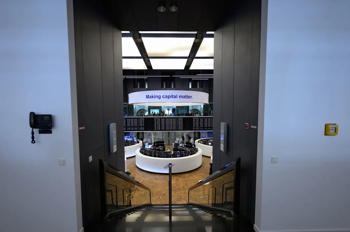 Trading floor of the Frankfurt Stock Exchange with digital displays showing European market indices.