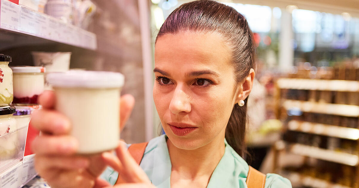 Consumer inspecting product packaging in a supermarket, illustrating the impact of new EU greenwashing rules on retail labels