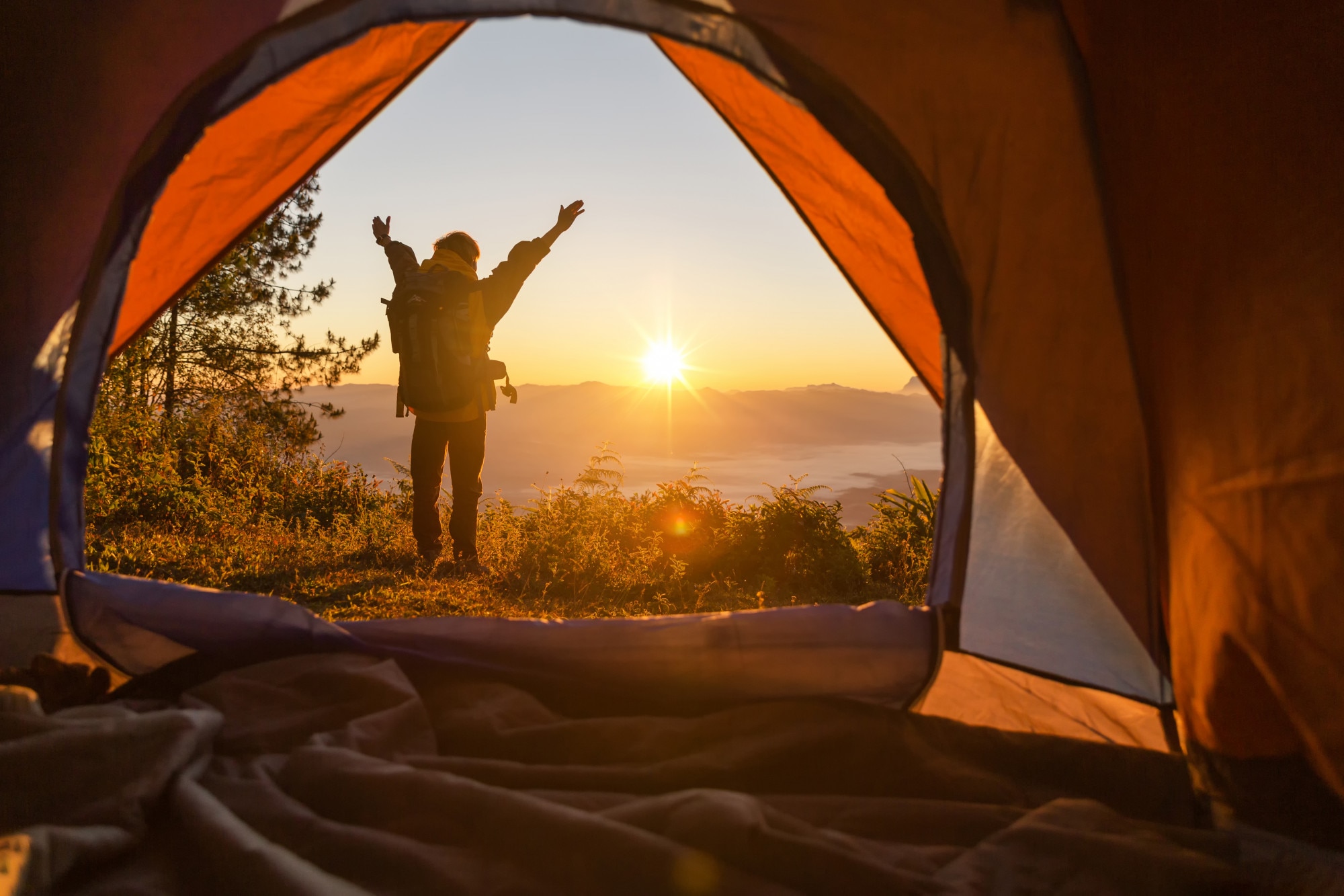 Hiker with tent and backpack in mountains