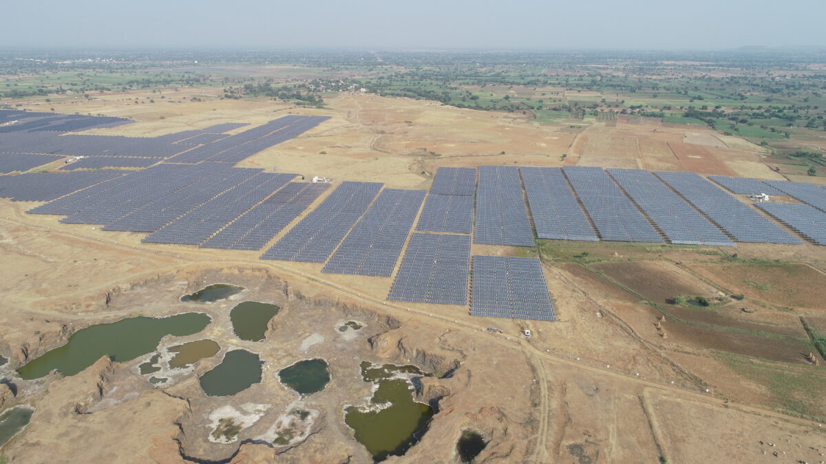 Solar power plant in Maharashtra, India, showing large-scale photovoltaic panels in a rural landscape