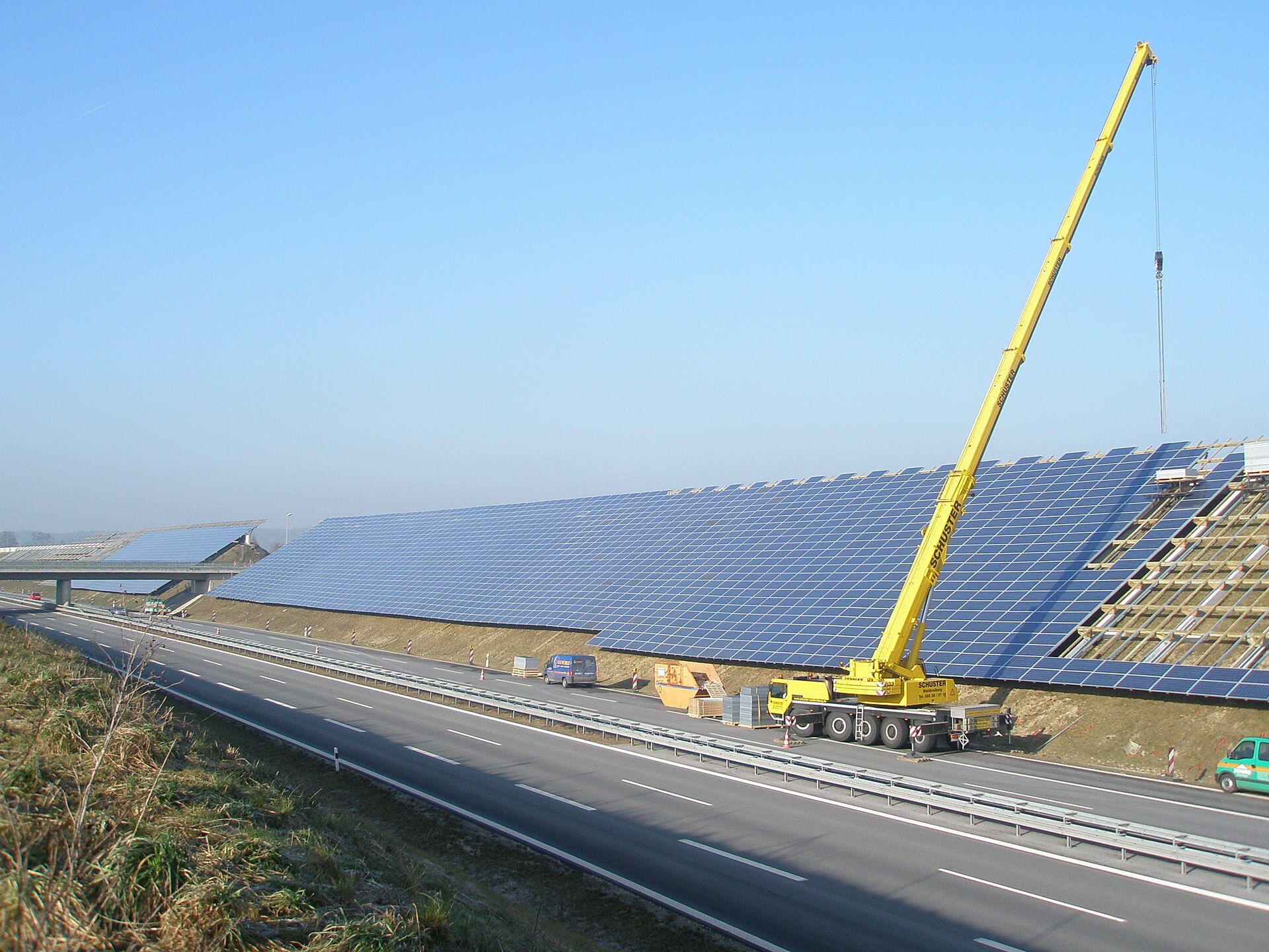 Solar panels installed along a highway noise barrier