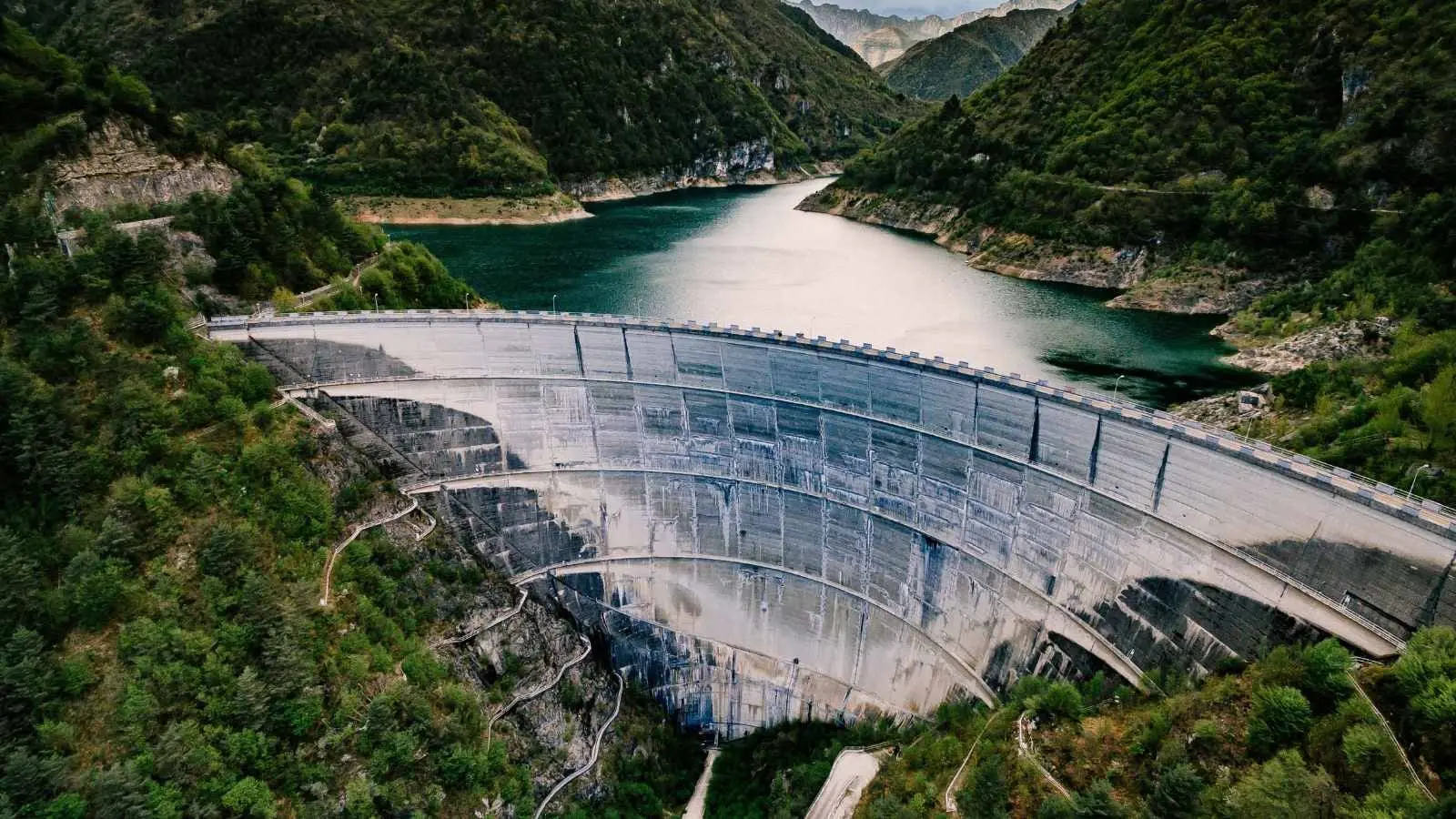 Hydroelectric power plant with wind turbines visible on hillside