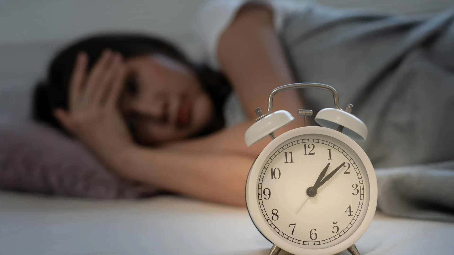 Asian woman awake in bed late at night — poor sleep schedules linked to dozens of serious diseases