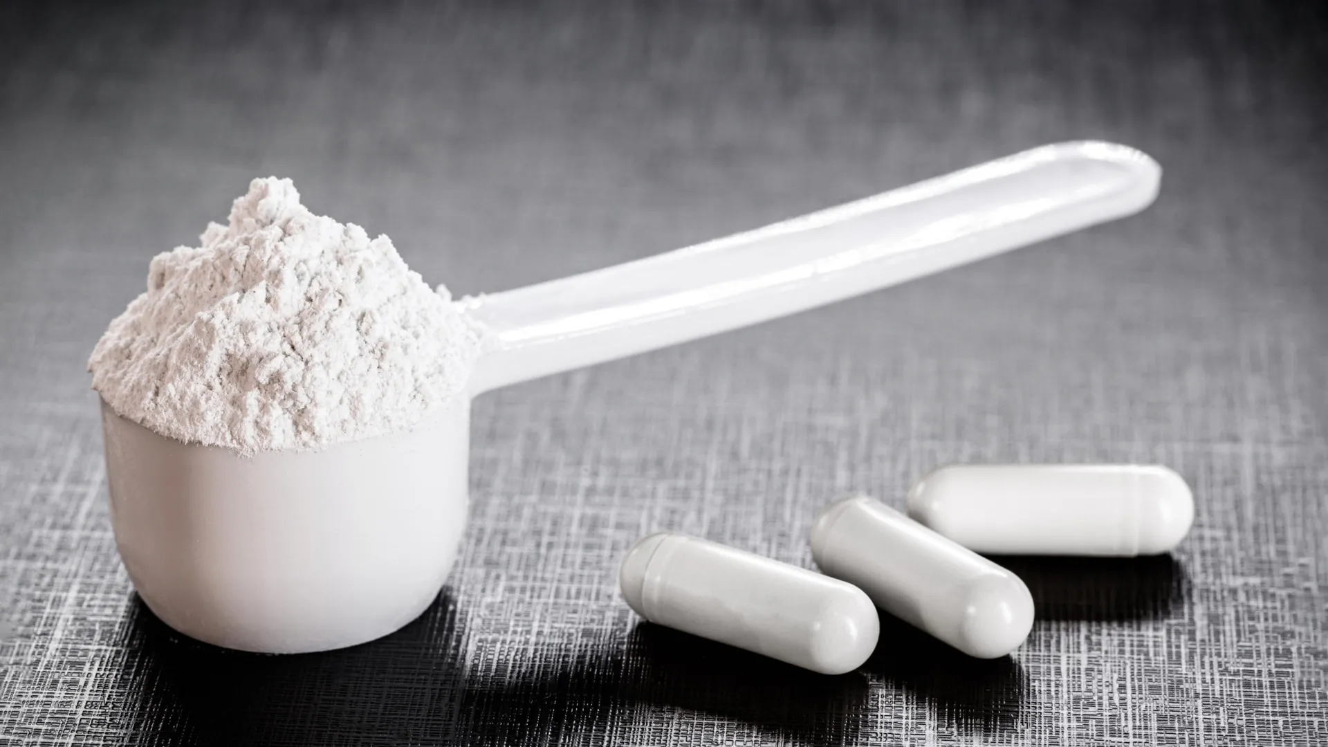 A photograph of creatine powder in a supplement container and sports nutrition context