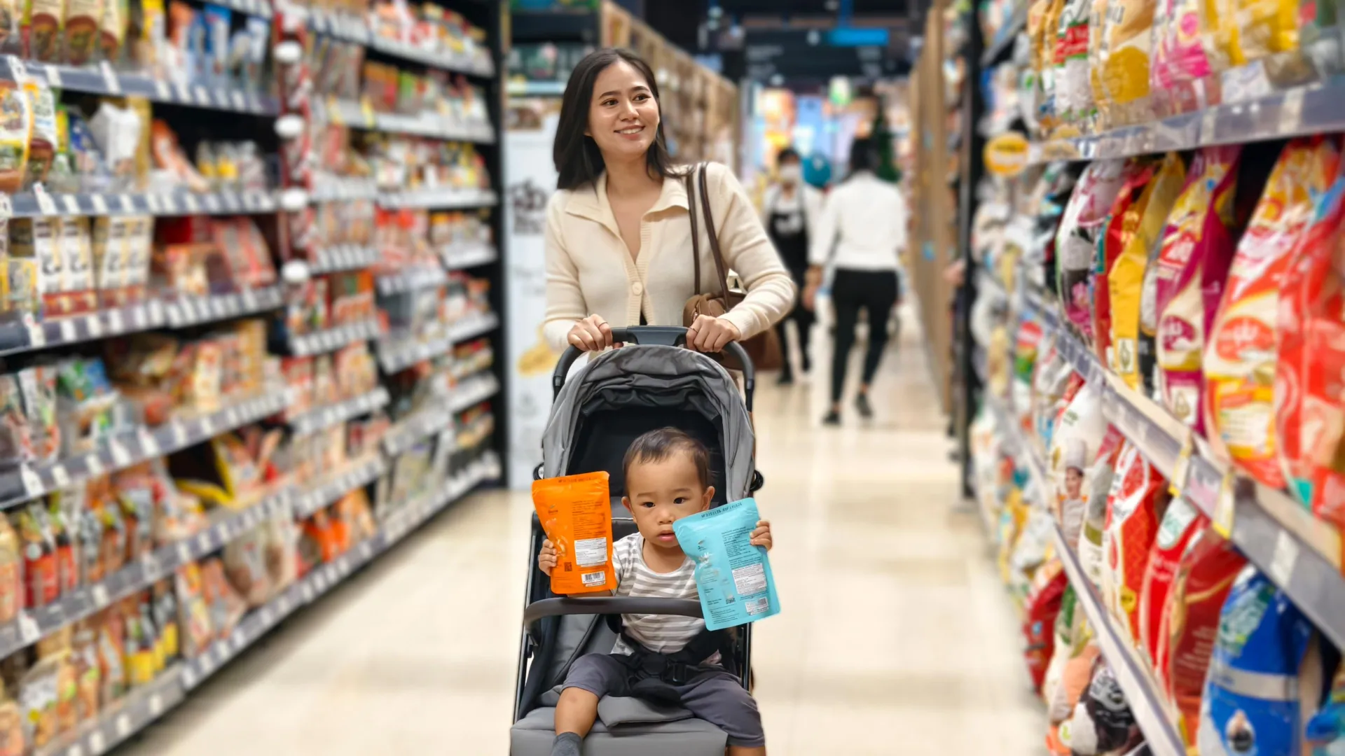 Woman pushing toddler stroller in grocery store snack aisle