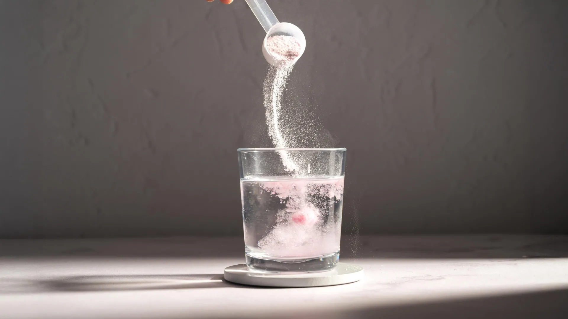 Pouring sport supplement powder in glass of water