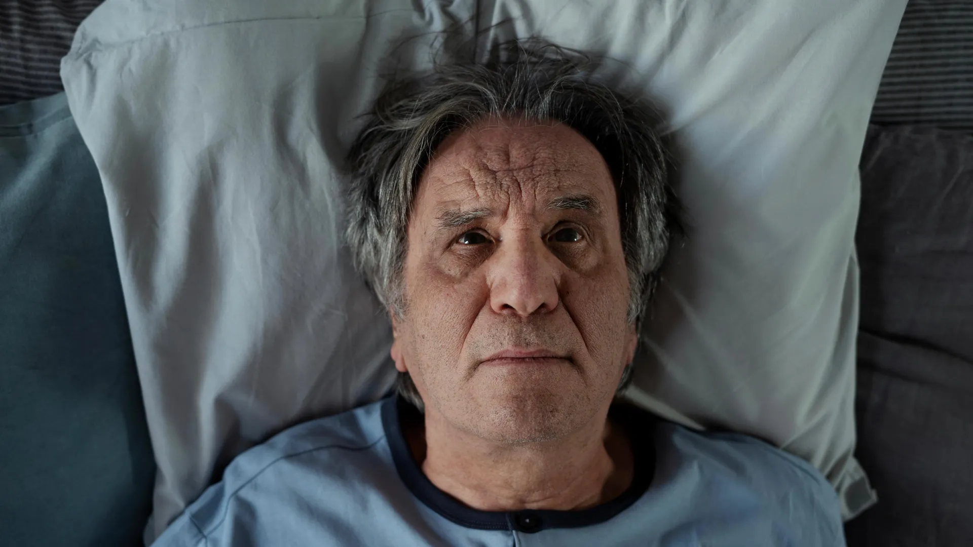 An older man stares forward, appearing tired and fatigued, illustrating the impact of chronic sleep deprivation